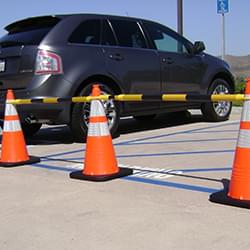 4' - 6.5' Black and Yellow Retractable Cone Bars (#15046A-CBYB) with 3x 28" Enviro-Cones cordoning off a handicap parking zone.