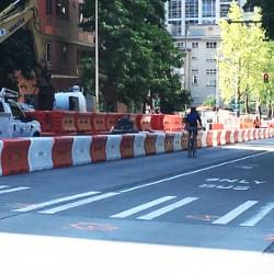 A series of TrafFix Water-Cable Barriers linked together along a roadway with a cyclist passing by